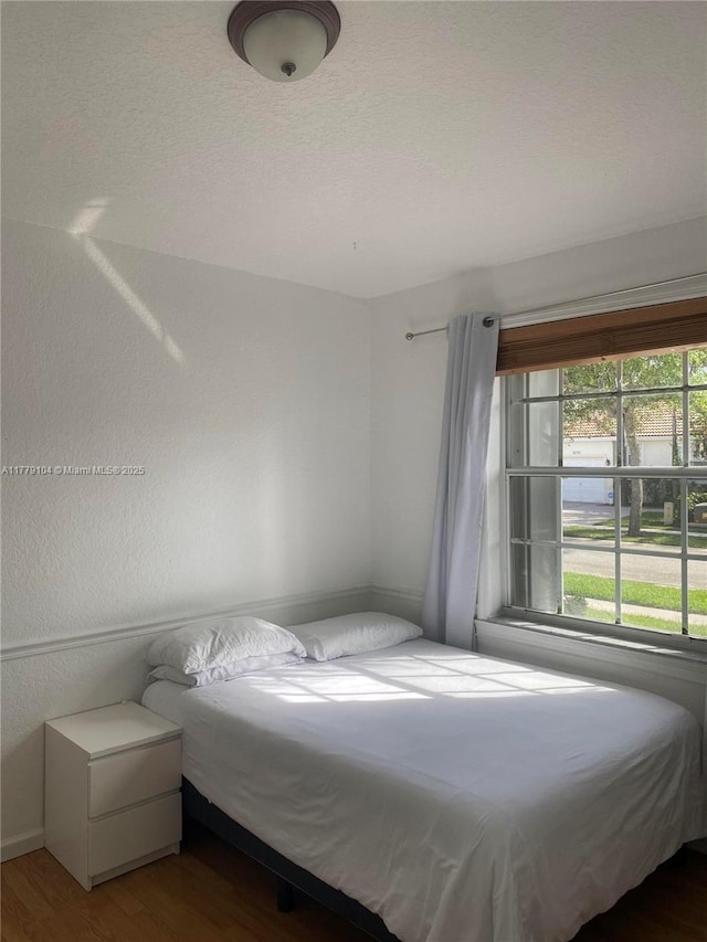 bedroom with a textured ceiling and wood finished floors