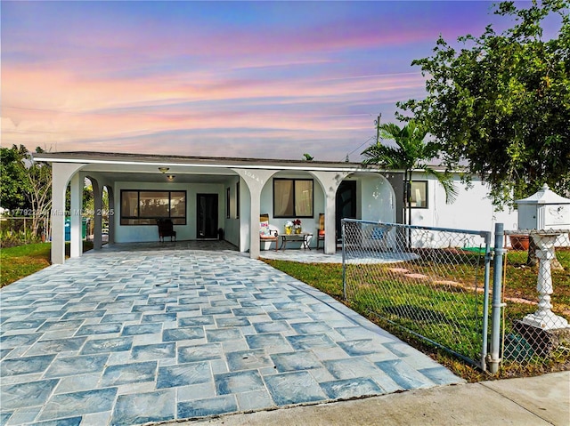 view of front facade with fence, a carport, stucco siding, and decorative driveway