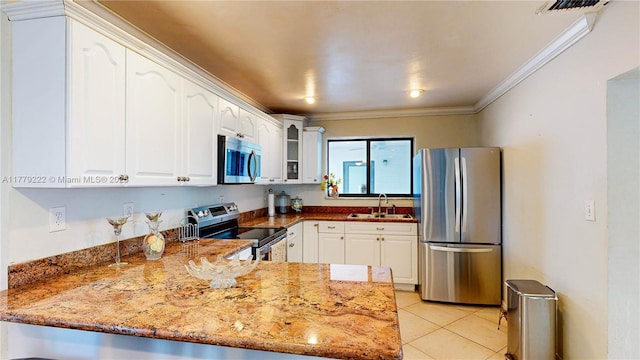 kitchen featuring glass insert cabinets, a sink, appliances with stainless steel finishes, a peninsula, and crown molding