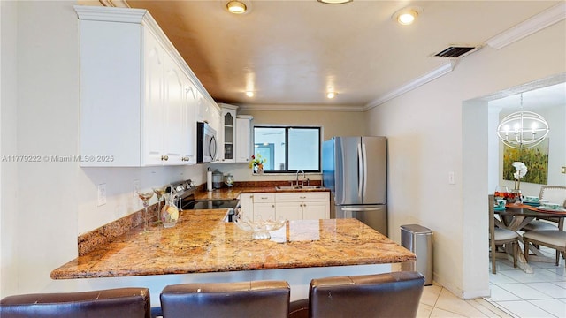 kitchen with an inviting chandelier, ornamental molding, a peninsula, appliances with stainless steel finishes, and a sink