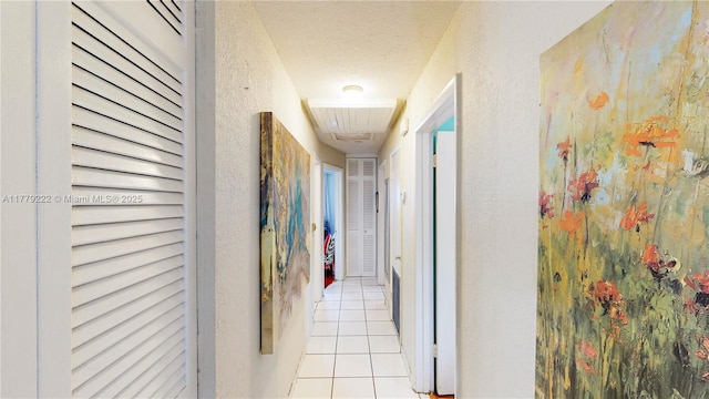 corridor with tile patterned floors, a textured wall, and a textured ceiling