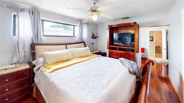 bedroom with a textured ceiling, wood finished floors, a ceiling fan, and visible vents