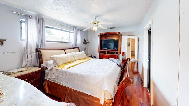 bedroom with visible vents, a ceiling fan, wood finished floors, and a textured ceiling