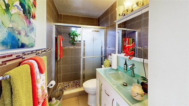 bathroom featuring tile walls, toilet, a shower stall, vanity, and tile patterned flooring