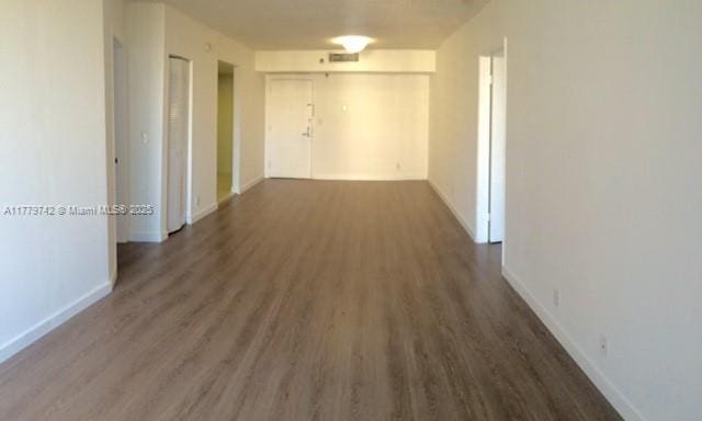 hall featuring wood finished floors, baseboards, and visible vents