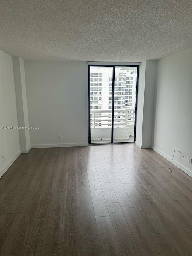 unfurnished room featuring baseboards, a textured ceiling, wood finished floors, and expansive windows