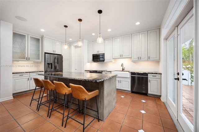 kitchen with tasteful backsplash, light tile patterned floors, appliances with stainless steel finishes, a kitchen bar, and a kitchen island