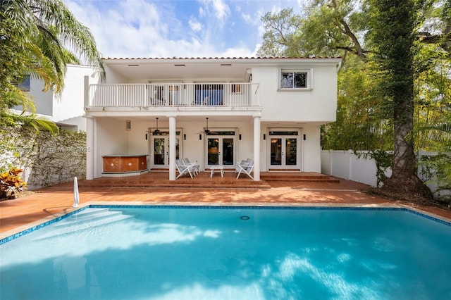 back of house featuring ceiling fan, fence, stucco siding, french doors, and a balcony