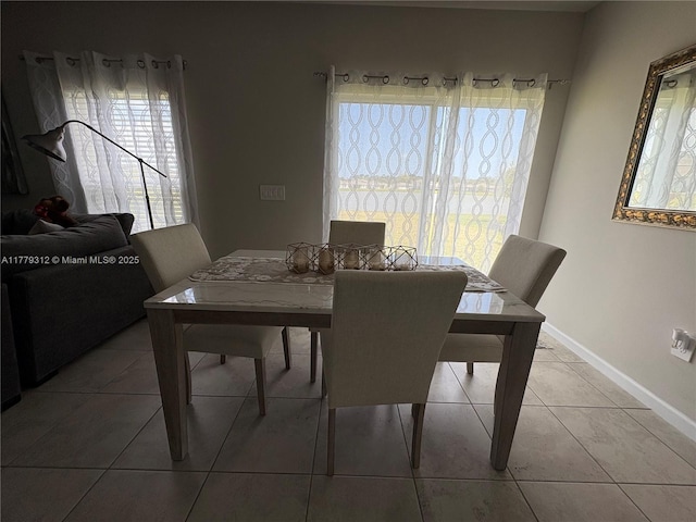 dining room featuring baseboards, tile patterned floors, and a water view