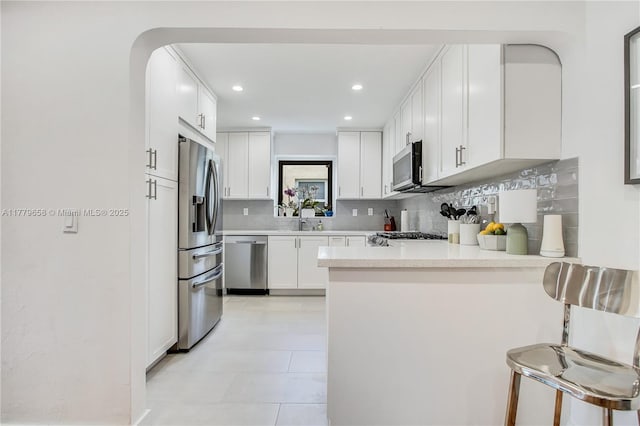 2019 SW 17th Ter, Miami, FL 33145 - kitchen featuring appliances with stainless steel finishes, a peninsula, tasteful backsplash, light countertops, and white cabinetry