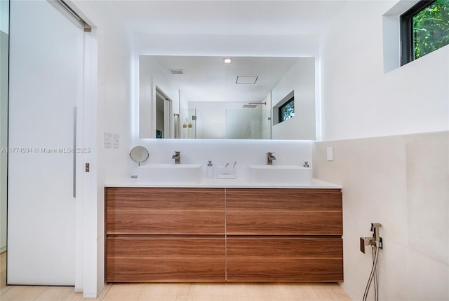 full bathroom featuring a walk in shower, double vanity, and a sink