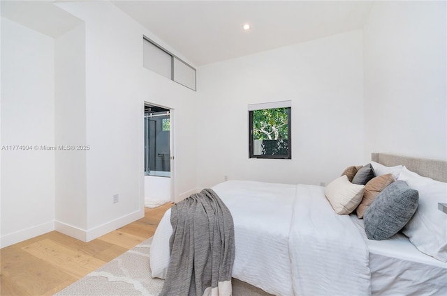 bedroom with baseboards, recessed lighting, ensuite bath, and wood finished floors
