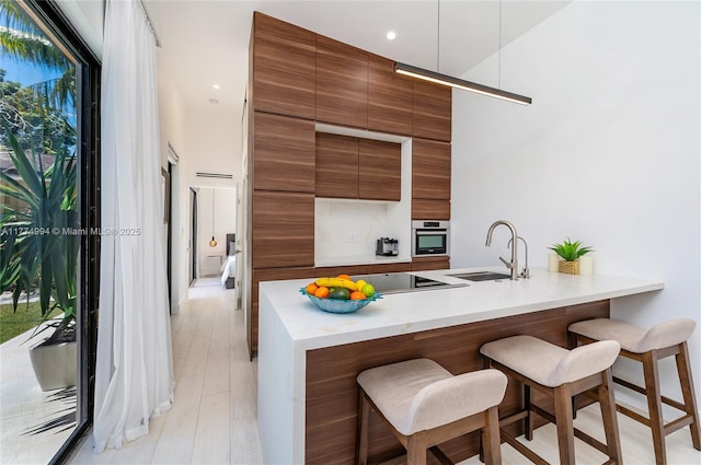 kitchen with a breakfast bar area, oven, a sink, and modern cabinets