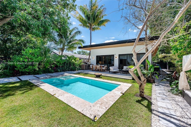 pool featuring a patio area, outdoor lounge area, and a lawn