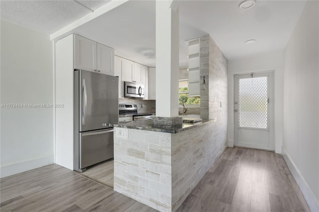 4200 Crystal Lake Dr Unit 303, Deerfield Beach, FL 33064 - kitchen featuring light wood-style floors, white cabinets, dark stone countertops, stainless steel appliances, and backsplash