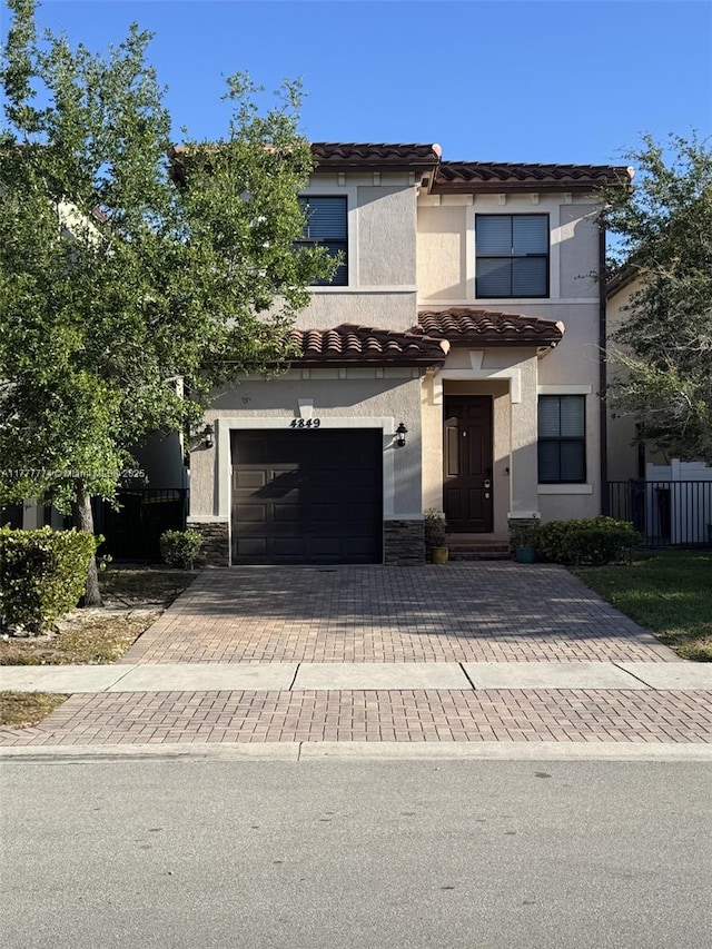 4849 NW 57th Ct, Tamarac, FL 33319 - view of front facade with a tiled roof, an attached garage, stone siding, stucco siding, and decorative driveway