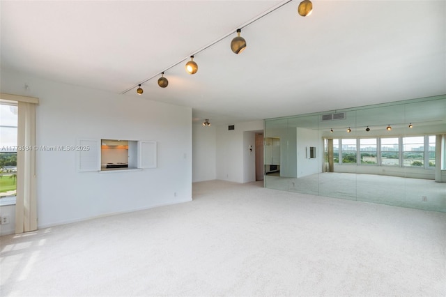 carpeted spare room featuring visible vents and rail lighting