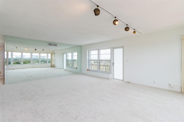unfurnished room with carpet flooring, rail lighting, and visible vents