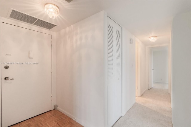 hall featuring baseboards, a notable chandelier, and visible vents