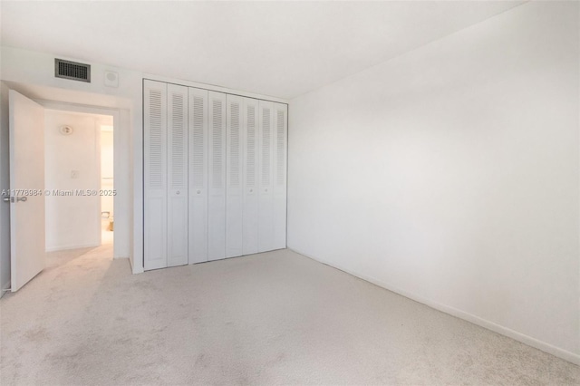 unfurnished bedroom featuring visible vents, carpet, baseboards, and a closet