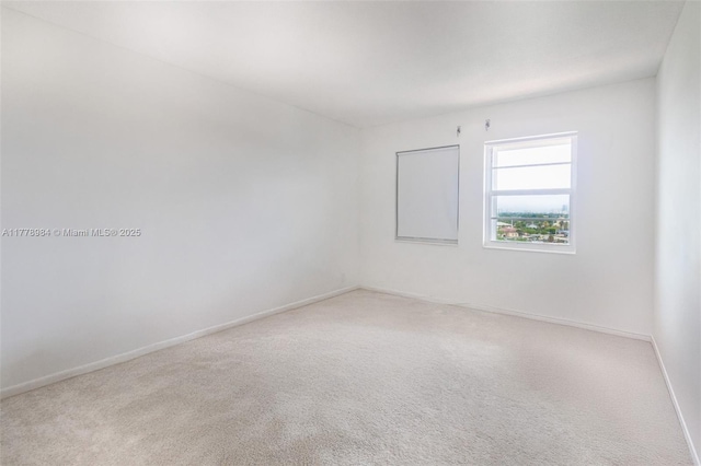 spare room featuring carpet floors and baseboards