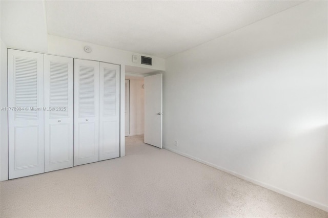 unfurnished bedroom with carpet floors, baseboards, a closet, and visible vents