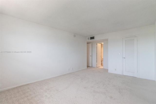 unfurnished room featuring baseboards, light colored carpet, and visible vents