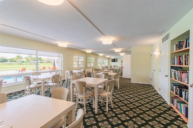 dining space with a textured ceiling, visible vents, baseboards, and carpet