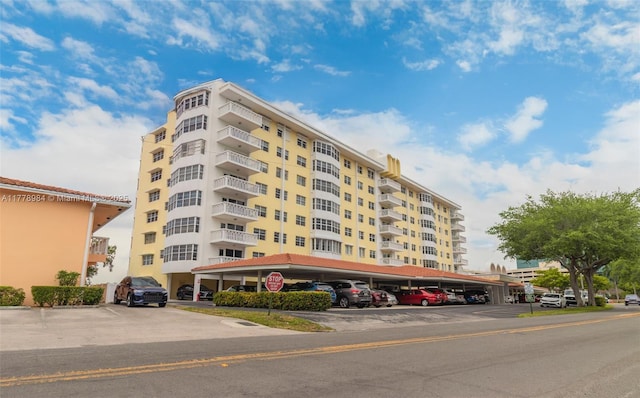view of building exterior featuring covered and uncovered parking