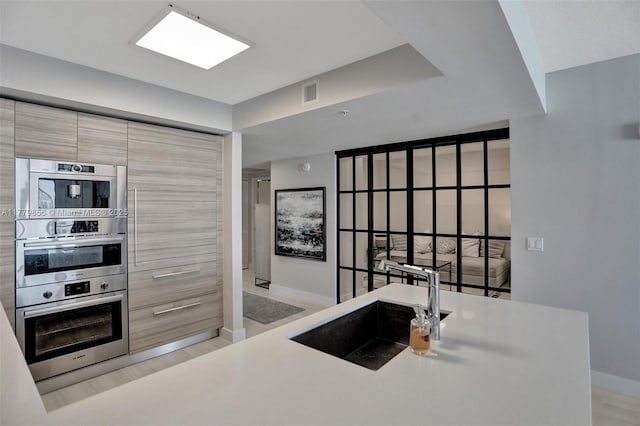 300 Sunny Isles Blvd Unit 4-903, Sunny Isles Beach, FL 33160 - kitchen with double oven, modern cabinets, light countertops, and light wood-style flooring