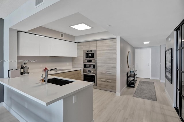 300 Sunny Isles Blvd Unit 4-903, Sunny Isles Beach, FL 33160 - kitchen featuring light countertops, modern cabinets, a peninsula, light wood-type flooring, and electric cooktop