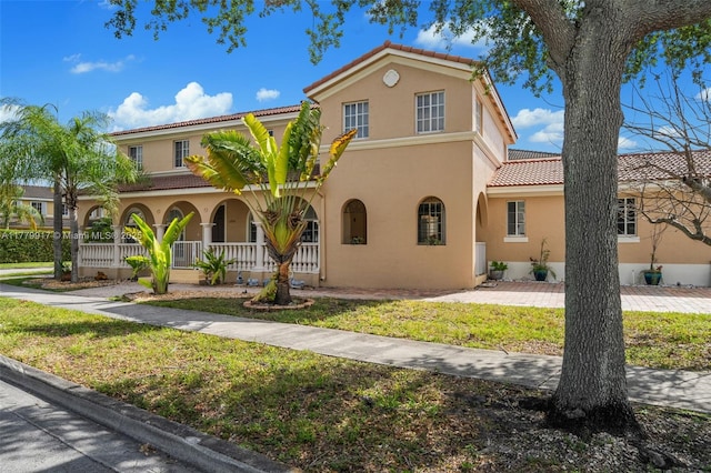 mediterranean / spanish house with a porch, stucco siding, and a tile roof