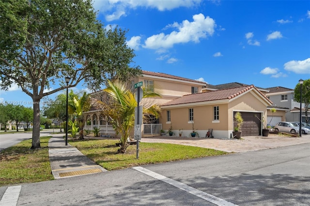 mediterranean / spanish home featuring a tile roof, an attached garage, driveway, and stucco siding