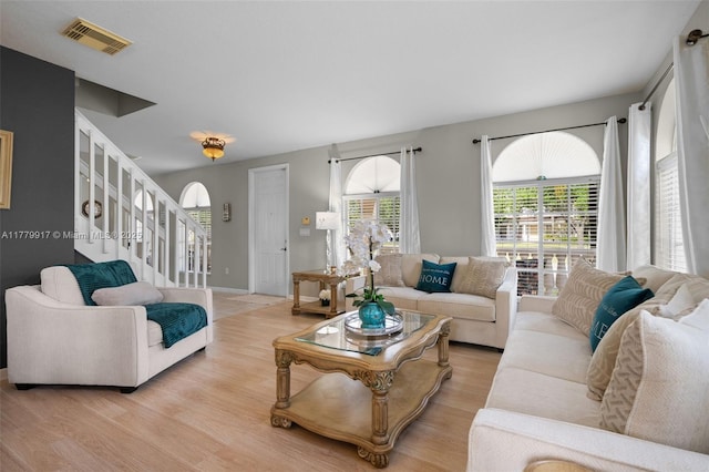 living area with visible vents, baseboards, stairway, and light wood finished floors