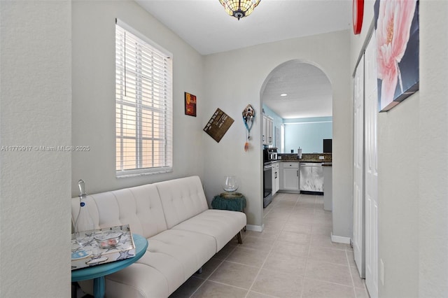 living room with arched walkways, baseboards, and light tile patterned flooring