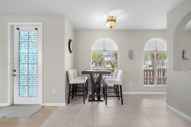 tiled dining area featuring arched walkways and baseboards