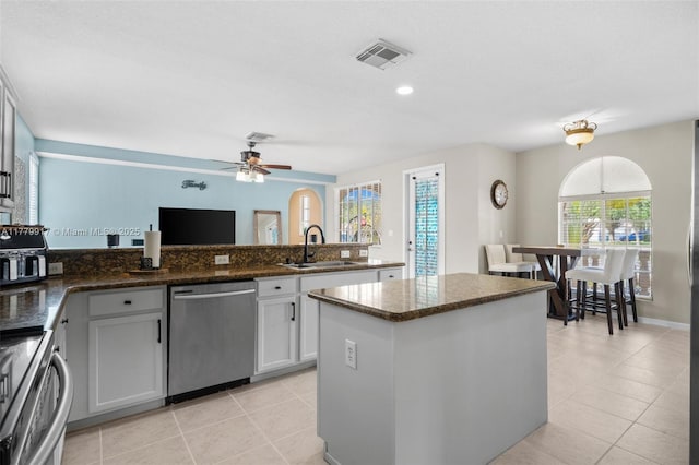 kitchen with visible vents, a center island, dishwasher, a sink, and a peninsula
