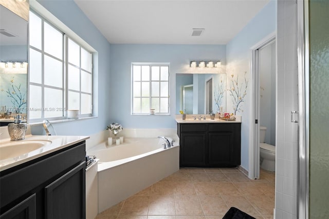 bathroom featuring toilet, a stall shower, a sink, and visible vents