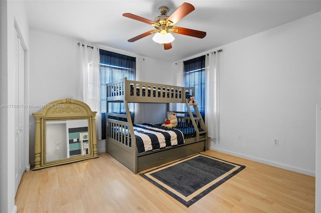bedroom featuring wood finished floors, ceiling fan, baseboards, and multiple windows