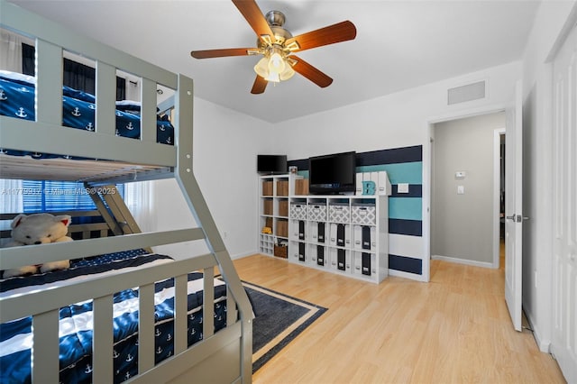 bedroom featuring wood finished floors, baseboards, a ceiling fan, and visible vents