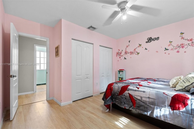 bedroom with baseboards, light wood-type flooring, two closets, a ceiling fan, and visible vents