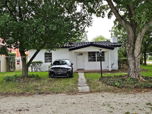 bungalow with stucco siding, a chimney, and a tile roof