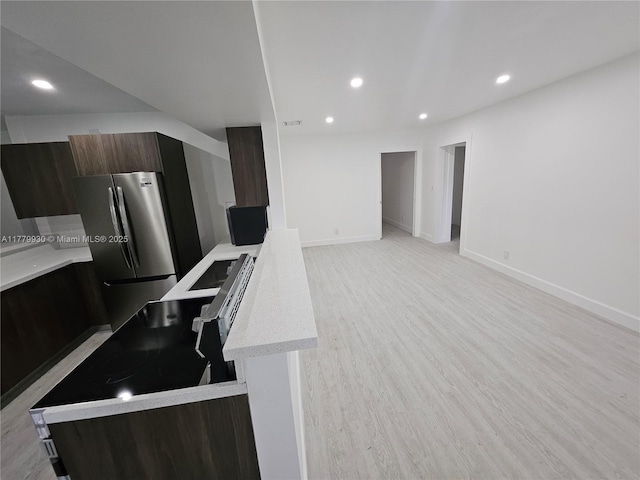 kitchen with recessed lighting, light countertops, freestanding refrigerator, light wood-style floors, and modern cabinets