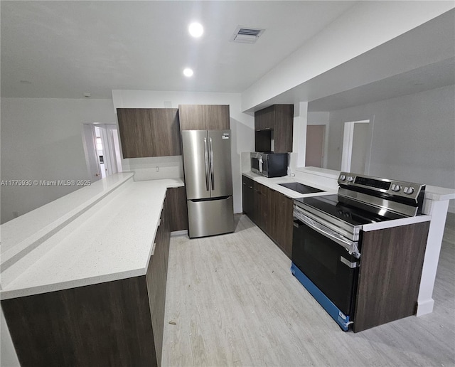 kitchen featuring visible vents, modern cabinets, light wood-style floors, a peninsula, and stainless steel appliances