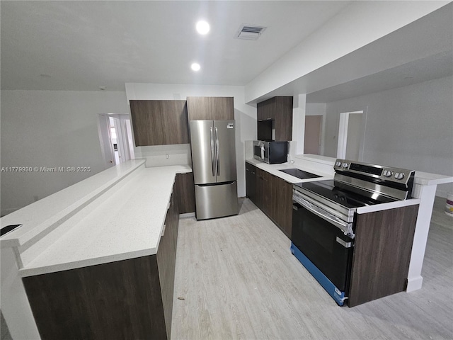 kitchen featuring modern cabinets, light wood-style flooring, a peninsula, appliances with stainless steel finishes, and light countertops