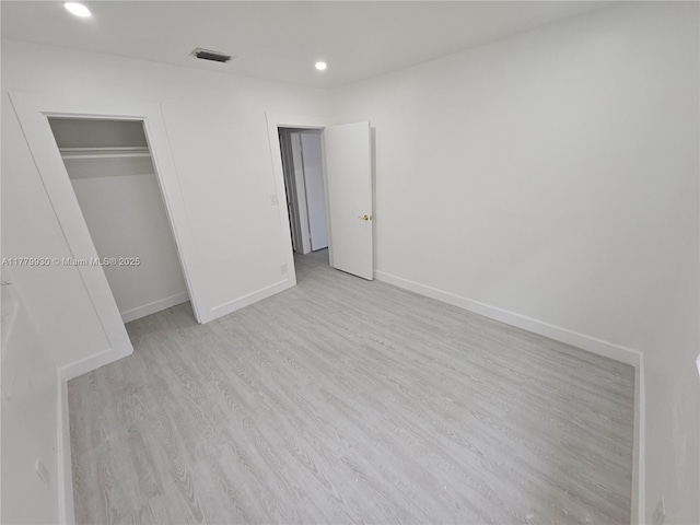 unfurnished bedroom featuring a closet, baseboards, recessed lighting, visible vents, and wood finished floors