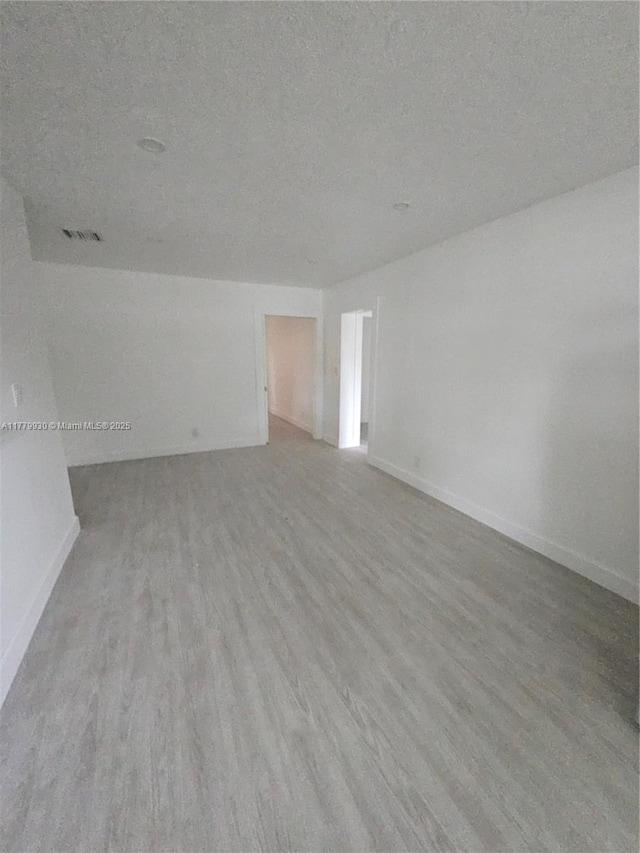 empty room featuring visible vents, baseboards, and wood finished floors