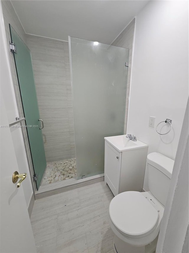 full bath with a shower stall, vanity, and toilet