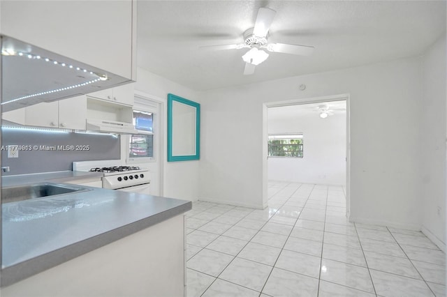 2001 N 26th Ave, Hollywood, FL 33020 - kitchen featuring white range with gas stovetop, white cabinetry, a ceiling fan, under cabinet range hood, and light tile patterned floors