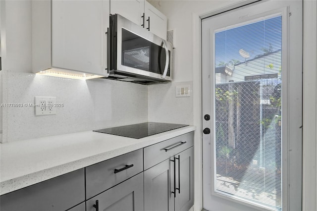2001 N 26th Ave, Hollywood, FL 33020 - kitchen with stainless steel microwave, black electric cooktop, backsplash, and gray cabinetry